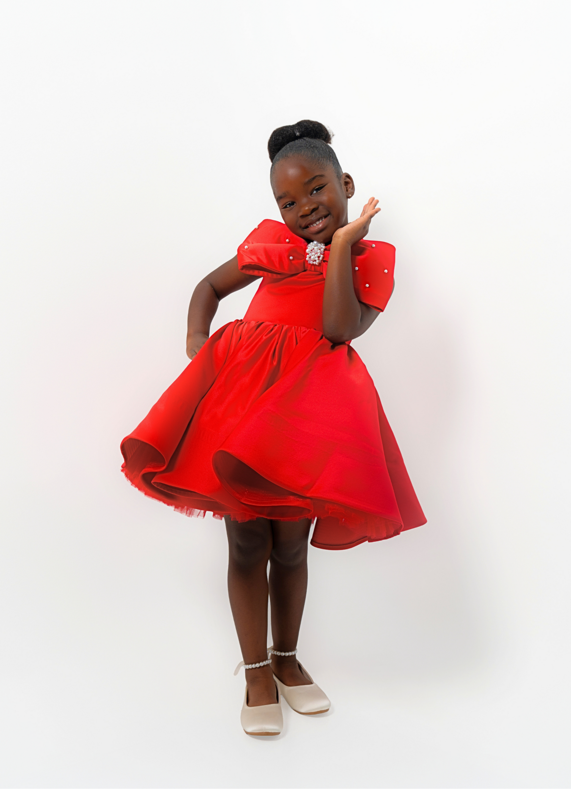 Girl in red satin dress with rhinestone bow, styled for Valentine’s Day or Christmas party