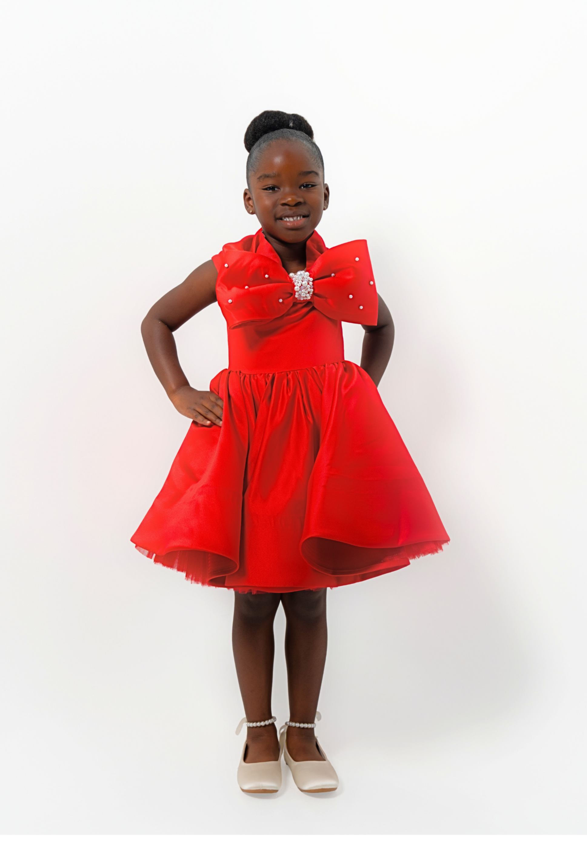 Girl in red satin dress with rhinestone bow, styled for Valentine’s Day or Christmas party