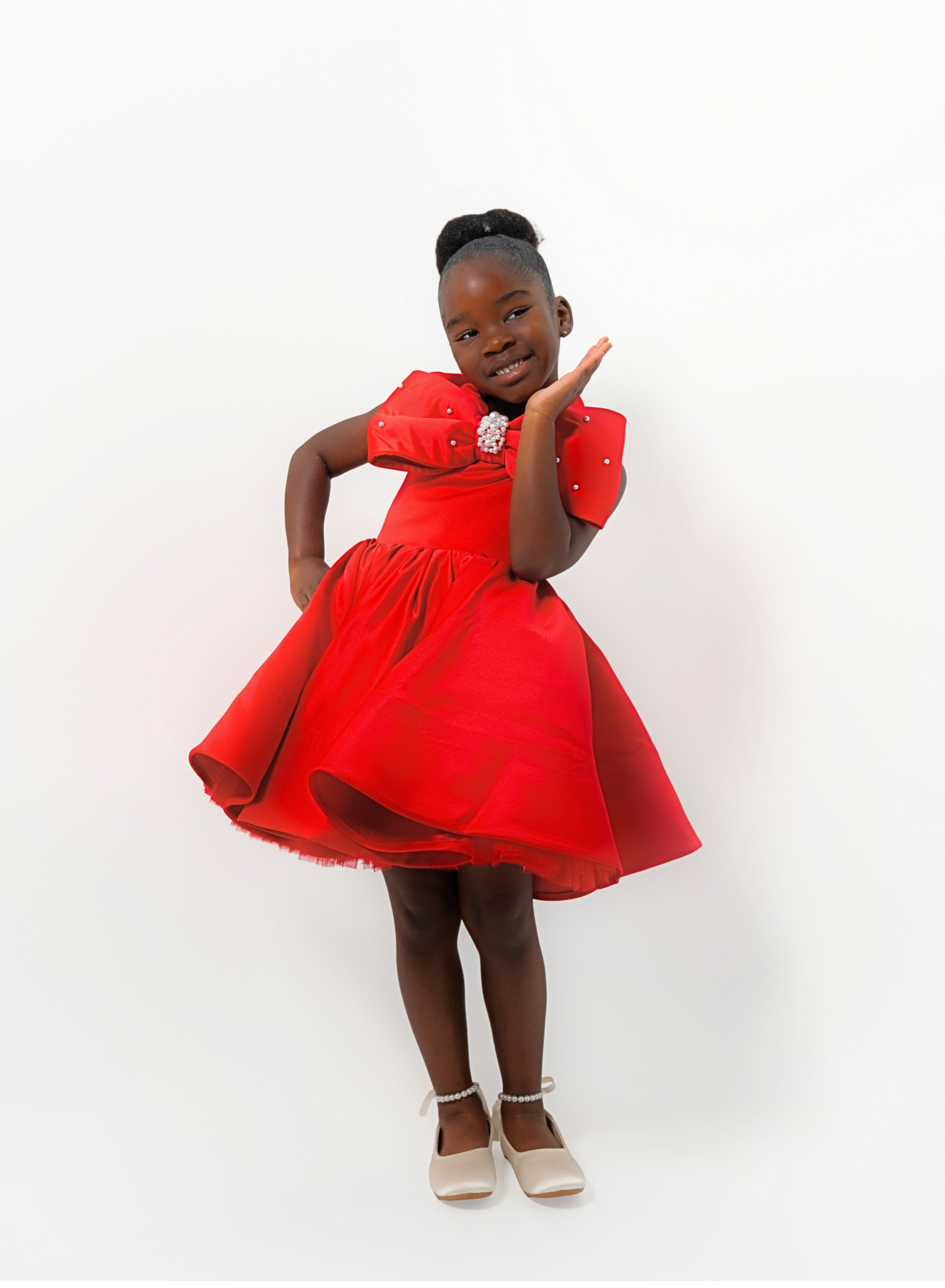 Girl in red satin dress with rhinestone bow, styled for Valentine’s Day or Christmas party