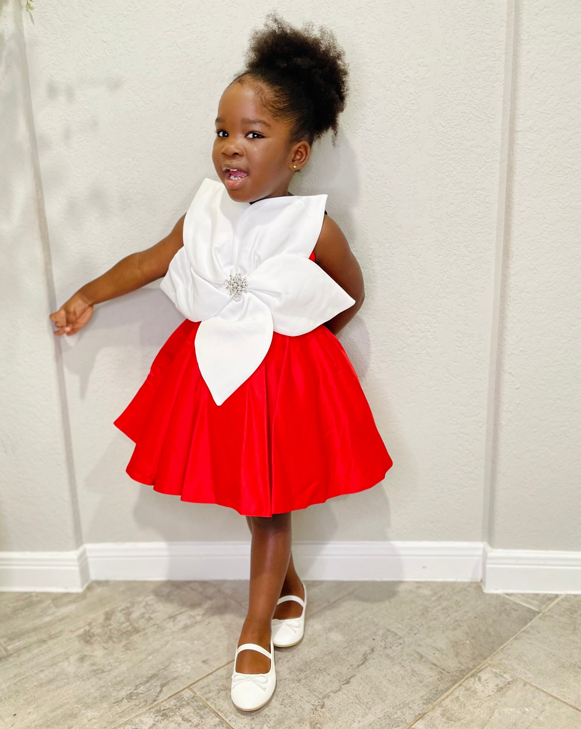 Girl wearing red holiday dress with white bow and brooch, ideal for Christmas or Valentine’s events