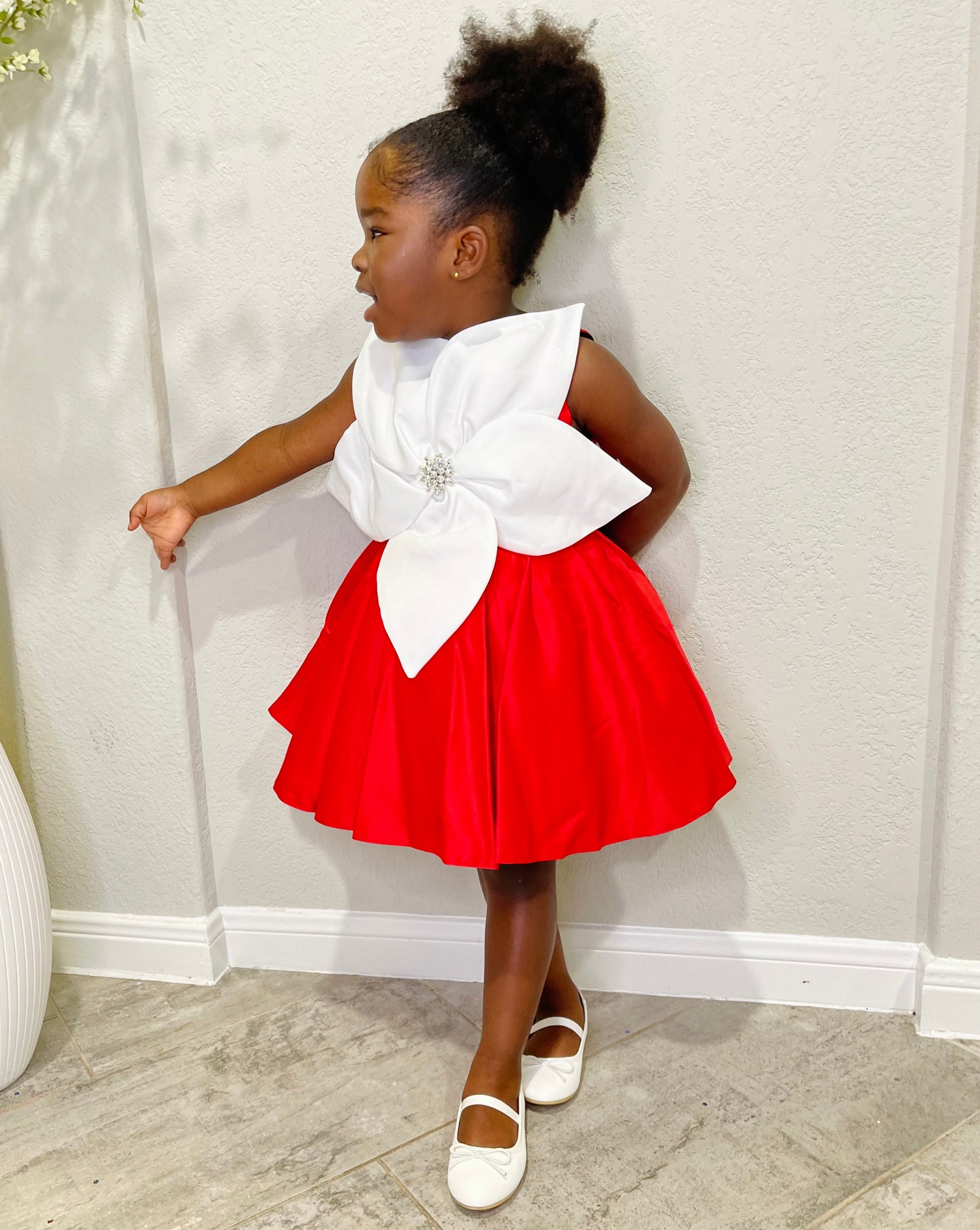 Girl wearing red holiday dress with white bow and brooch, ideal for Christmas or Valentine’s events