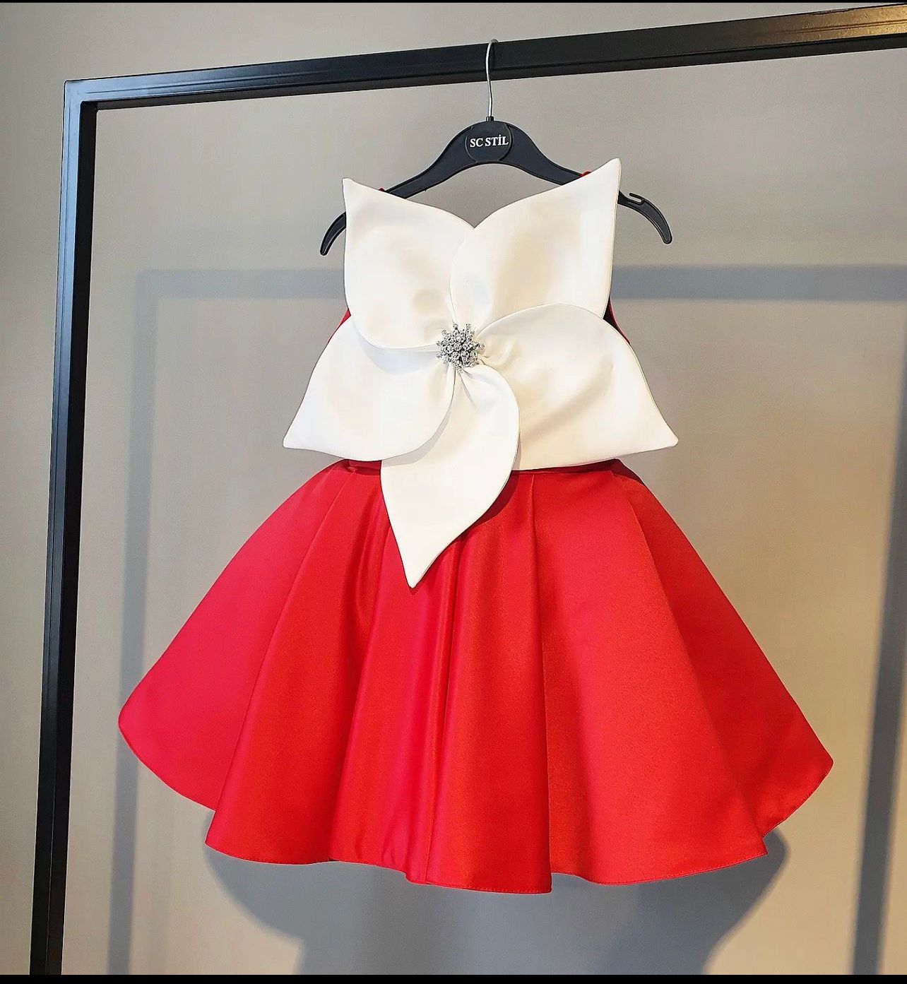 Girl wearing red holiday dress with white bow and brooch, ideal for Christmas or Valentine’s events