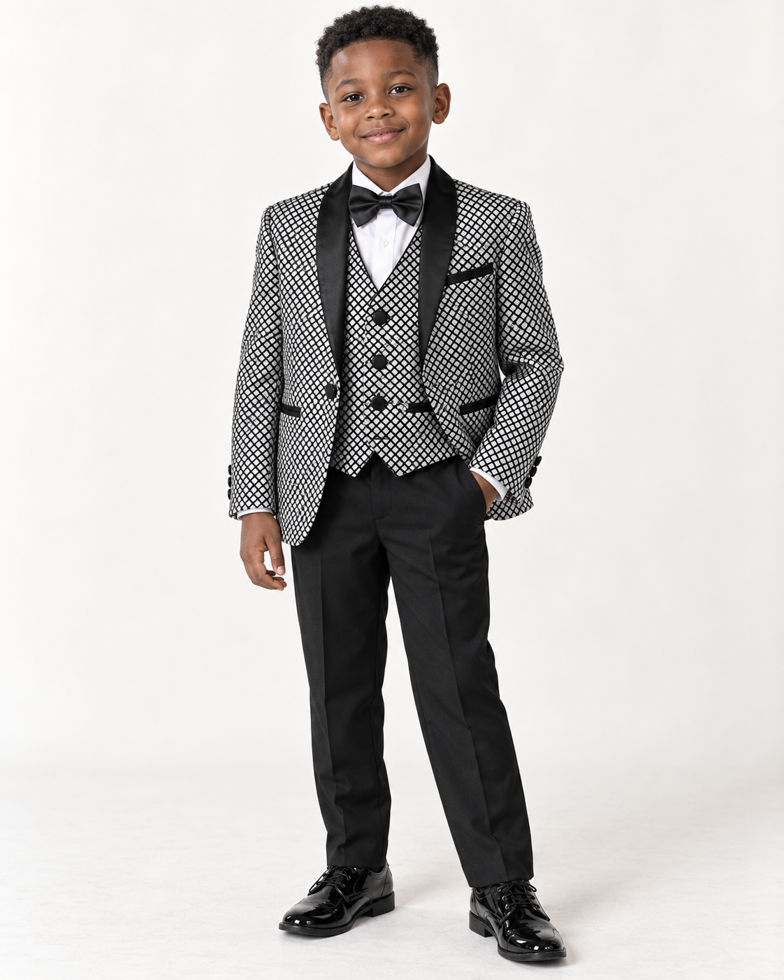 Black boy wearing black and white shimmery five-piece tuxedo, front view