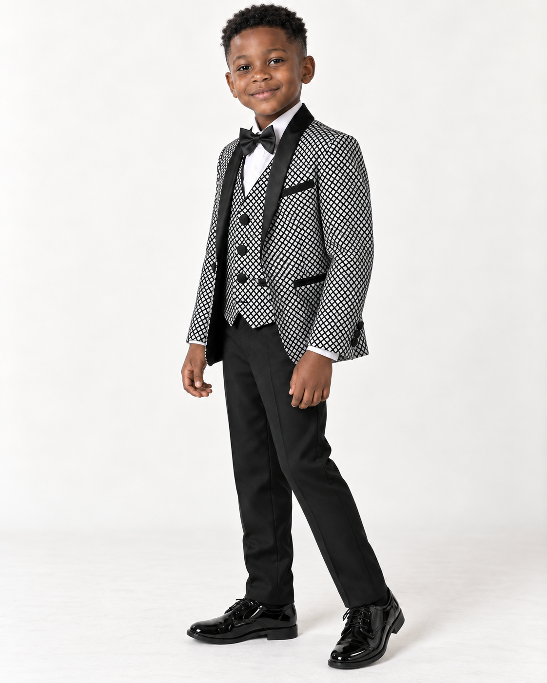 Black boy wearing black and white shimmery five-piece tuxedo, side-angle view