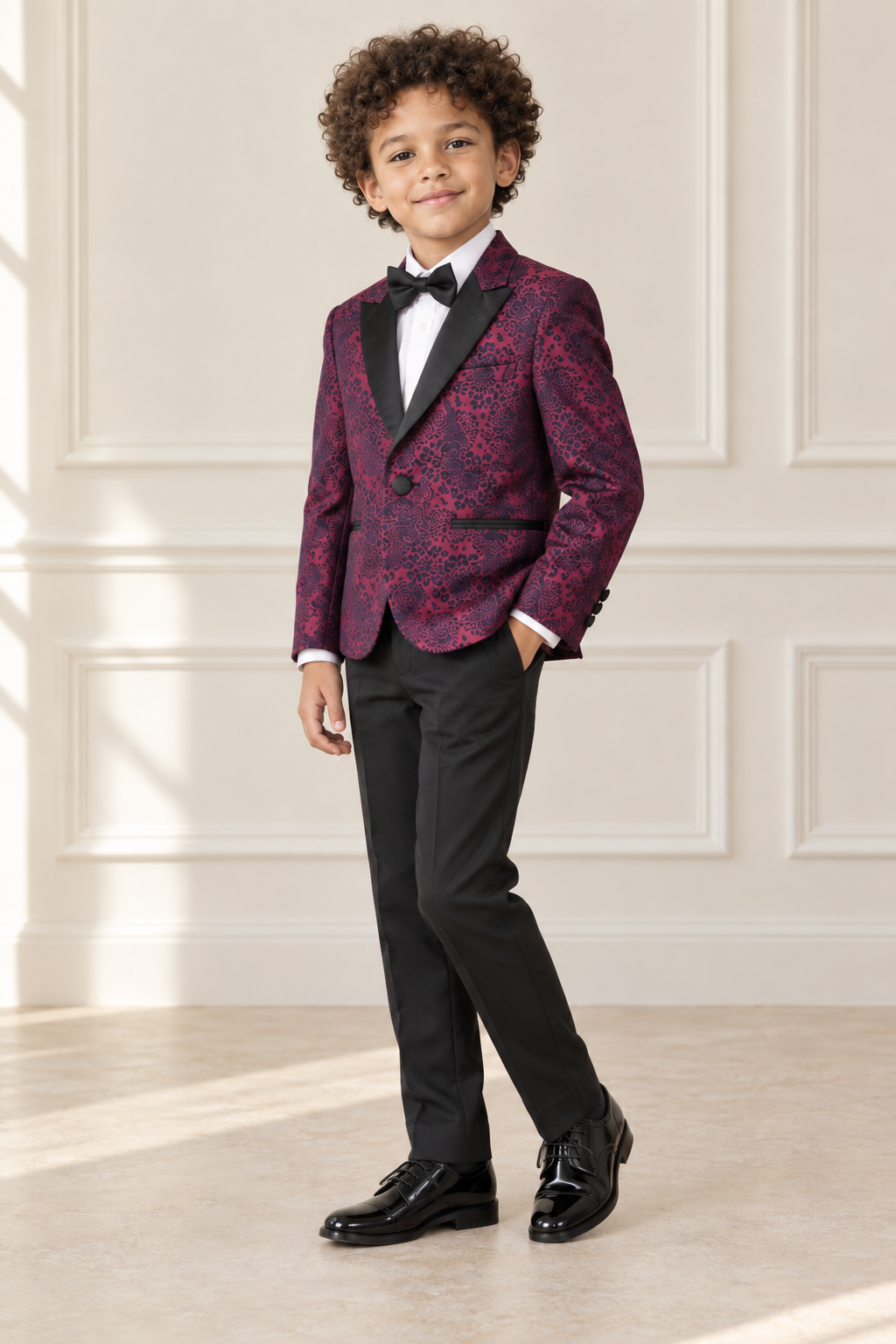Mixed-race boy wearing burgundy patterned formal suit, angled view
