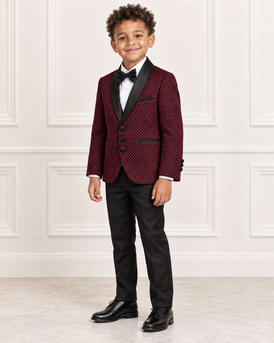 Mixed-race boy around age 8 wearing the burgundy shimmery five-piece tuxedo suit, natural three-quarter view