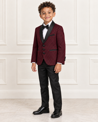 Mixed-race boy around age 8 wearing the burgundy shimmery five-piece tuxedo suit, natural three-quarter view